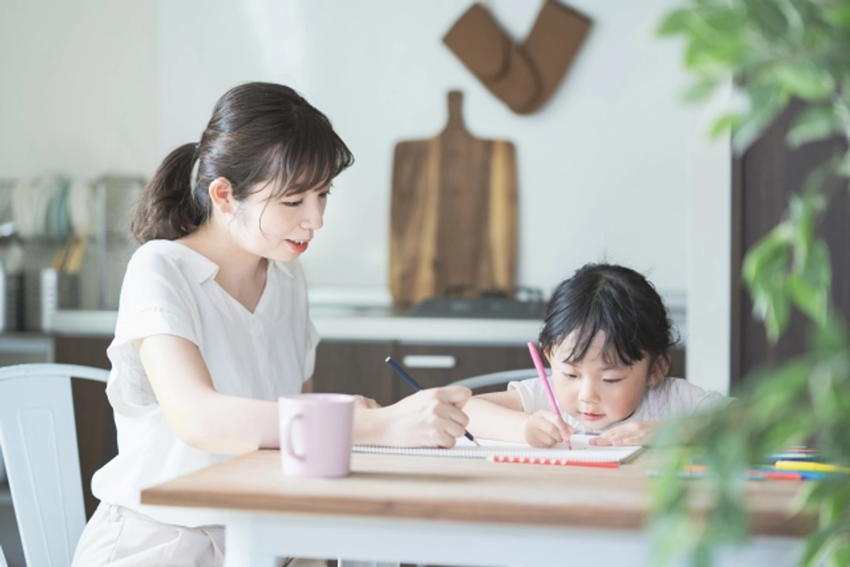 ダイニングテーブルで勉強する子供と見守る母