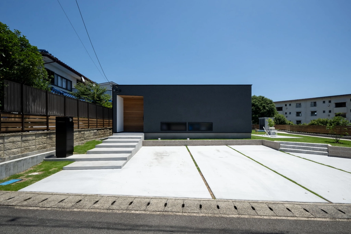 広い駐車場のあるシンプルな黒い平屋の家